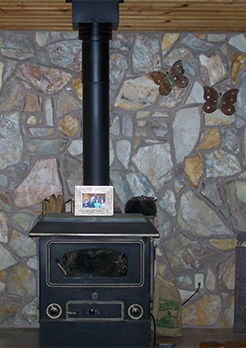 wood stove set in front of a stone masonry wall