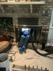 Technician In Fireplace Sweeping The Flue With Booties & A Tarp